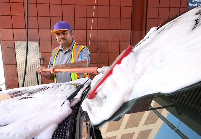 Staff member foaming a car at Royal Oak Car Wash